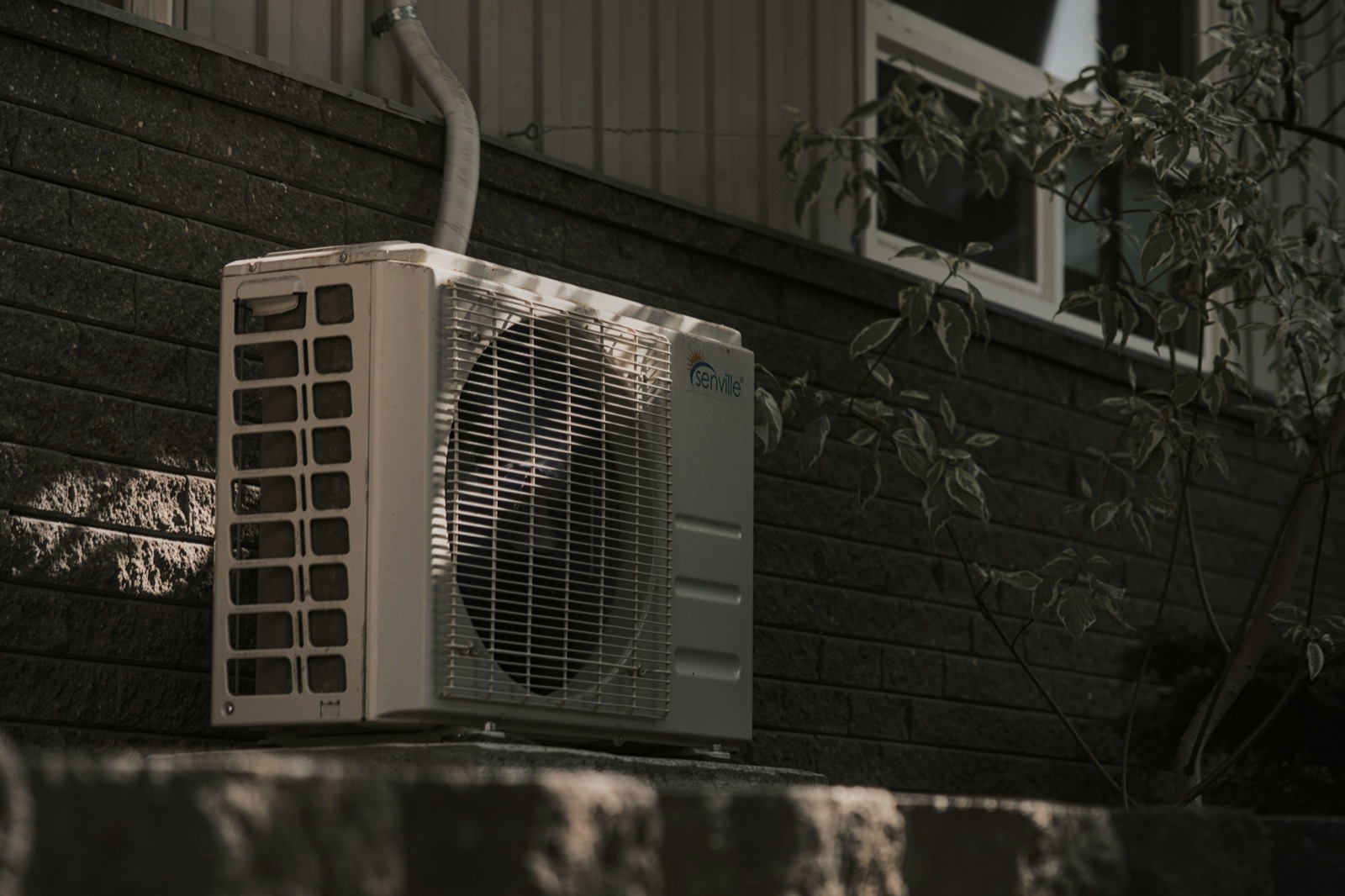 An outdoor HVAC condenser unit beside a house